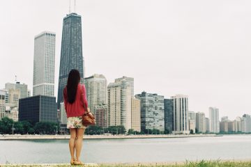 A woman in a red sweater stands and looks out at the Chicago skyline