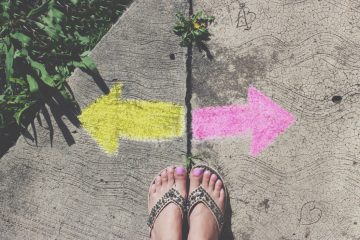 This photo shows a woman's feet on a sidewalk. There are two arrows, a yellow one pointing left and a pink one pointing right.