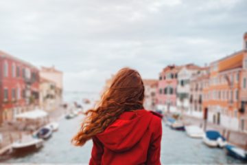 A woman gazes out over a bridge in Venice Italy. We discuss whether or not travel rewards credit cards are worth having