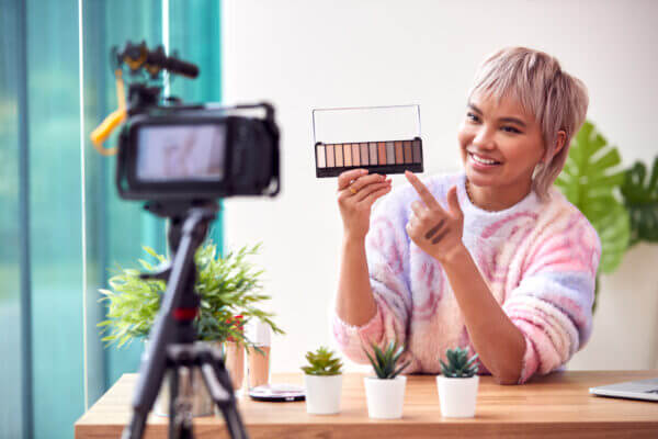 Woman wearing a tye dye sweater creating a tiktok video in her home