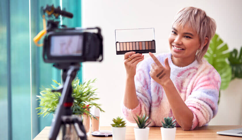 Woman wearing a tye dye sweater creating a tiktok video in her home