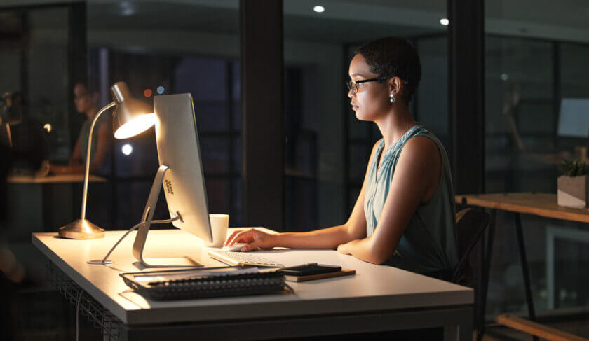 A woman works at her computer at night, studying a diversified stock portfolio