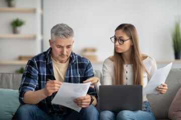 Couple sitting on a couch reviewing Investments to Avoid During a Recession