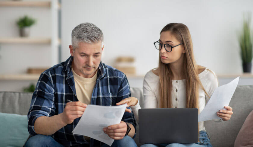 Couple sitting on a couch reviewing Investments to Avoid During a Recession