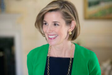 Sallie Krawcheck, founder of Ellevest, wearing a green cardigan and smiling. She discusses imposter syndrome and how women can stop it once and for all.