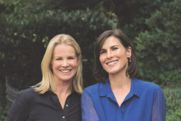 Katty Kay wearing black and Claire Shipman wearing blue and smiling at the camera. We discuss women in power in this podcast episode.