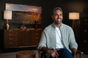 Ramit Sethi wears a gray jacket and smiles confidently.