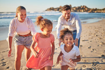 A family running on beach in summer; this article explores how much life insurance you need