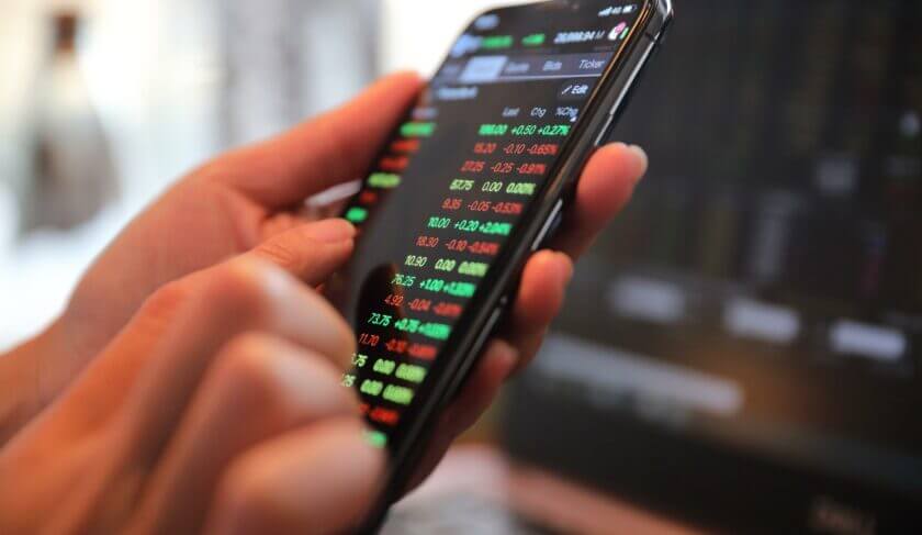 Woman's hand holding a smart phone showing stock exchange trading chart. Are you taking on too much stock market risk?