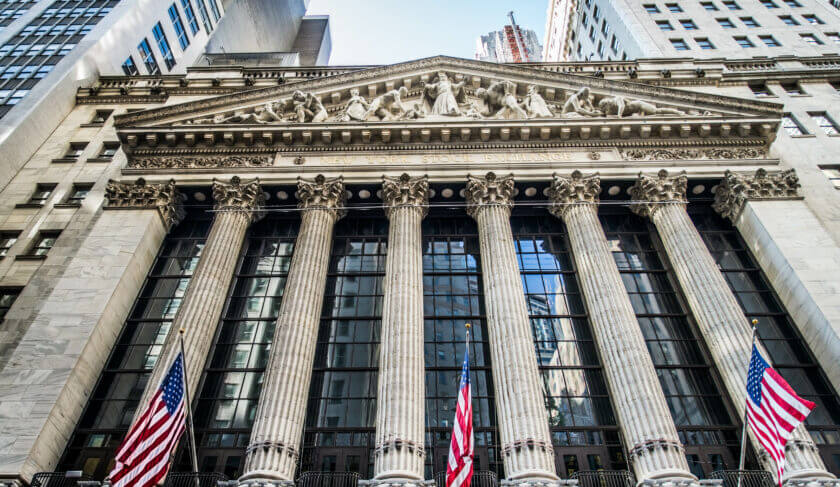 The Facade of the Wall street Stock exchange looms large over downtown Manhattan, with American flags flying. This article examines the challenges female founders face to get funding.