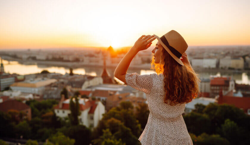 A woman looks out at panoramic view of a European city at sunset. In this article, Ramit Sethi weighs in on what a "rich" life really means