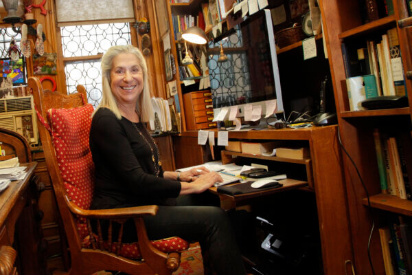 Letty Cottin Pogrebin sits at her desk, wearing black and smiles at the camera.