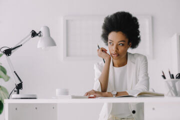 Women woking at a desk looking into the distance contemplating career growth.
