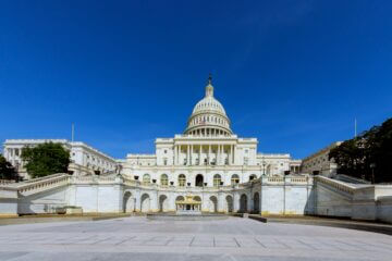 The U.S. Capitol building stands in Washington, D.C. against a sunny blue sky.