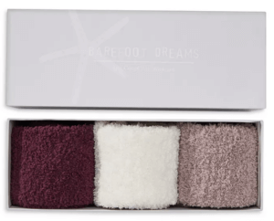 A gift box with three pairs of fuzzy socks is pictured. They are burgundy, white and taupe.