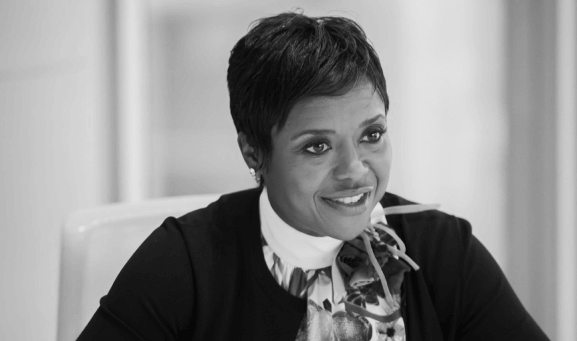 Headshot of Mellody Hobson in black and white talking at a conference wearing a scarf.