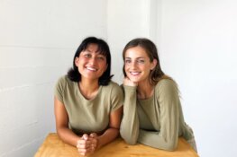 Oddli cofounders Jensen Neff and Ellie Chen wear sea green shirts and smile in front of a white background.