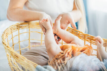 A baby's feet in her mother's hands. A mom cradles her daughter in a bassinet.